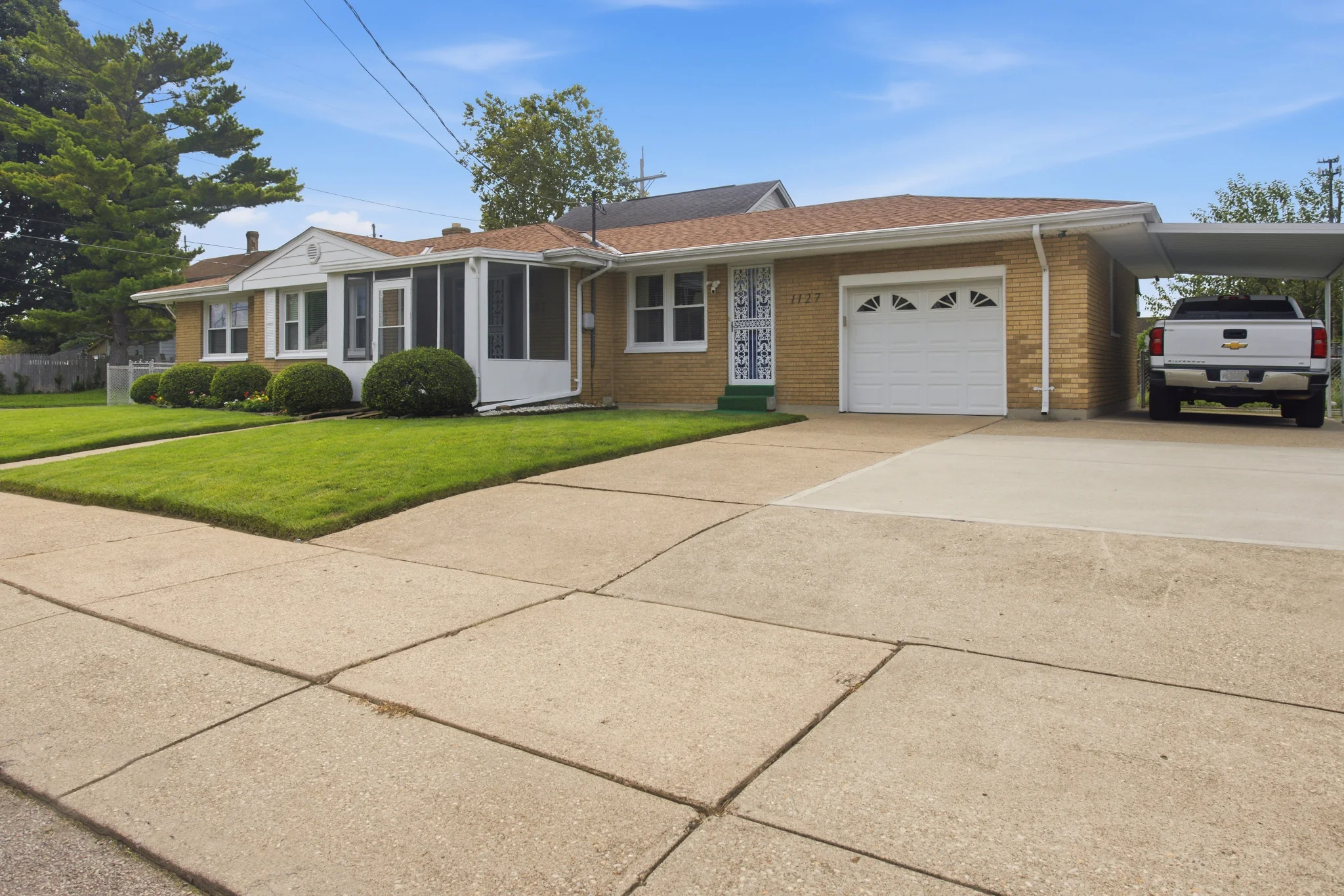 Exterior view showing garage, driveway and adjacent carport